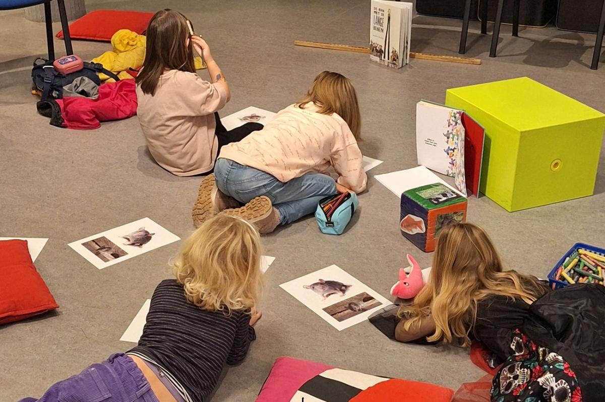 foto van kinderen op de grond met boeken en tekeningen