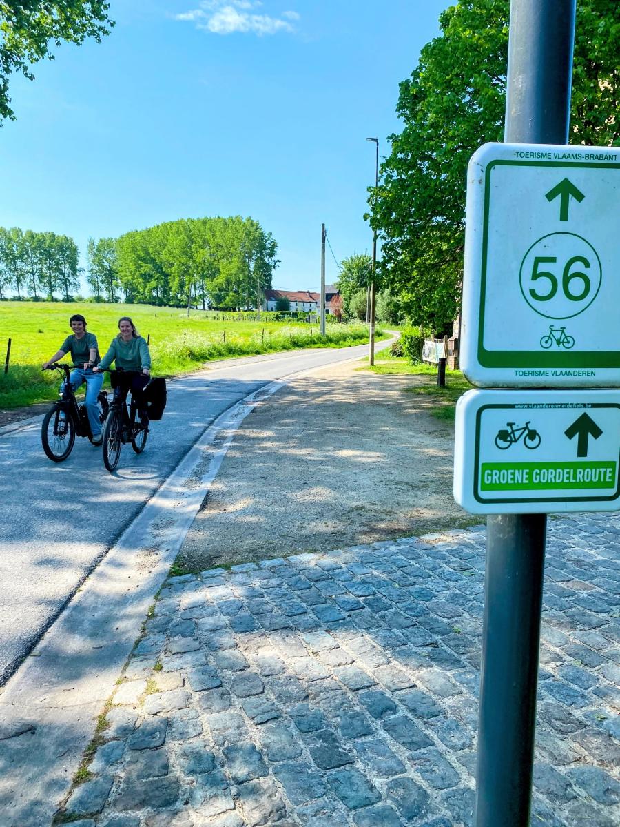 foto van bordje fietsroute met twee fietsers op de achtergrond