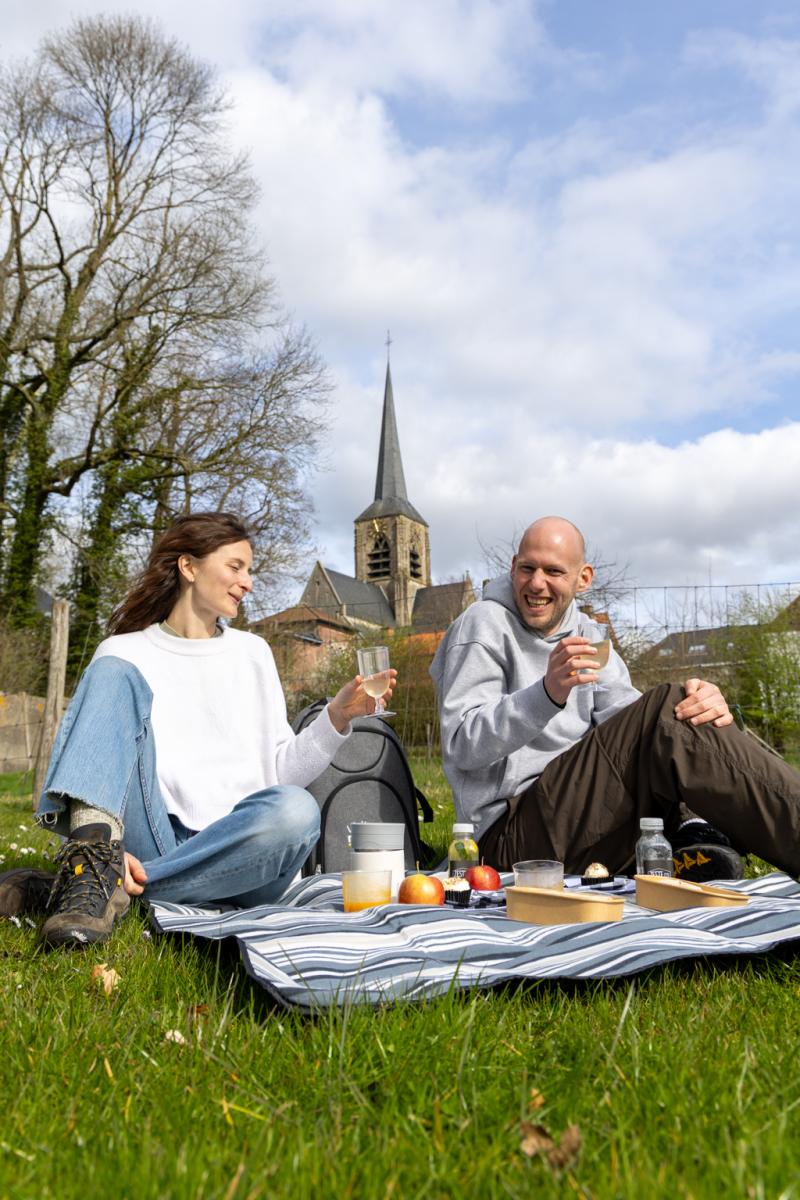 Twee mensen op een picknickdeken met kerktoren Sint-Martens-Bodegem op de achtergrond