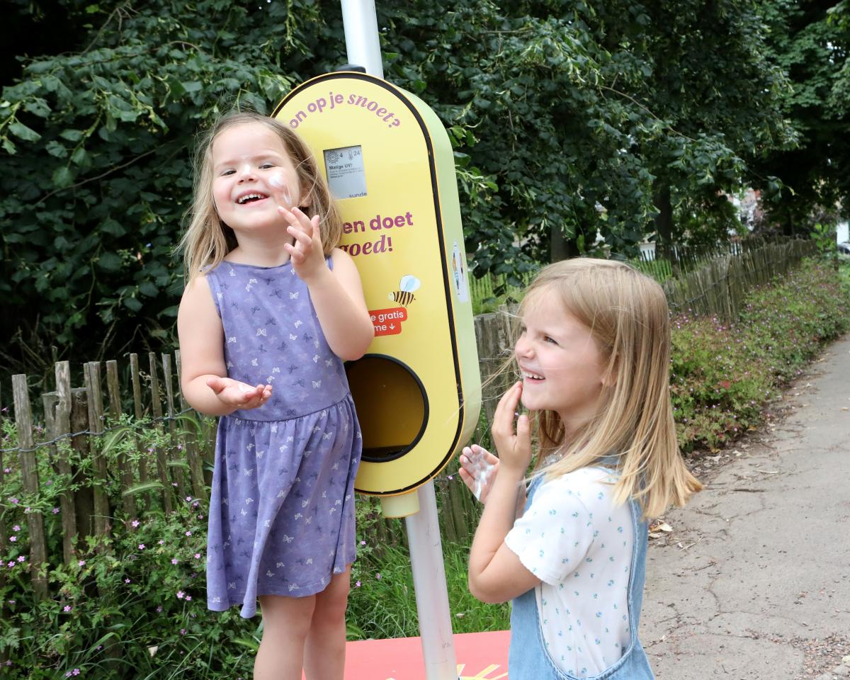 twee kinderen aan een paal met zonnecrème