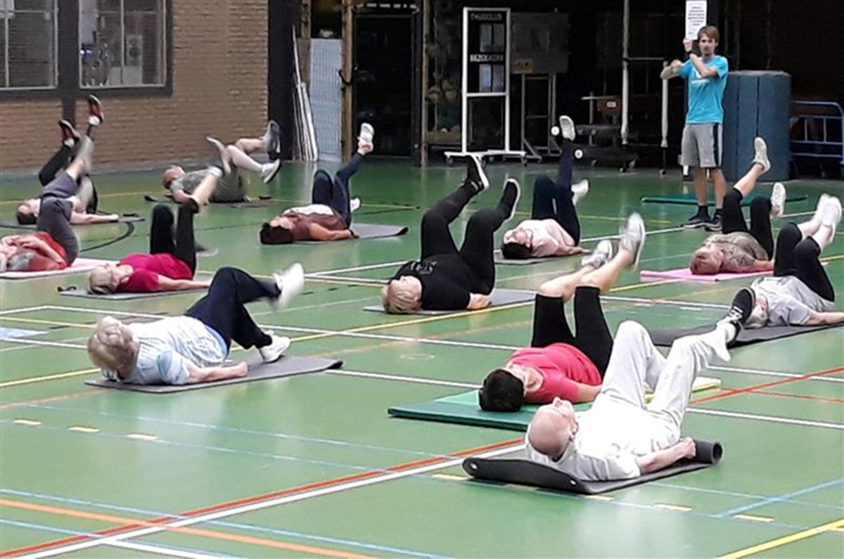 mensen in sportzaal op fitnessmatje met de benen in de lucht