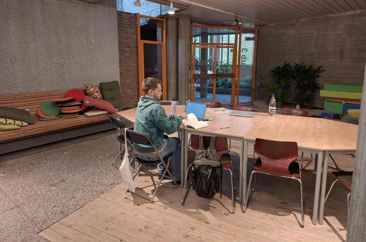jongen aan grote tafel met studieboeken