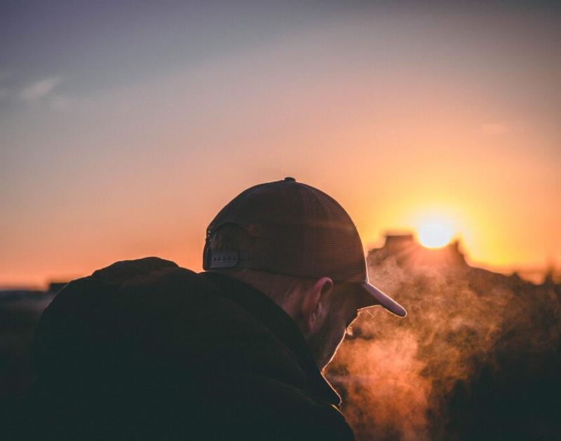 man met pet in zonsondergang