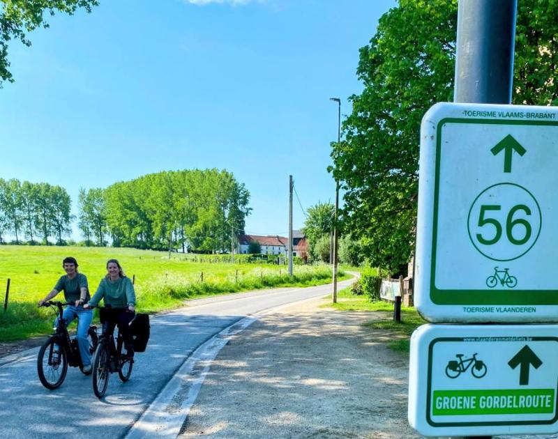 foto van bordje fietsroute met twee fietsers op de achtergrond
