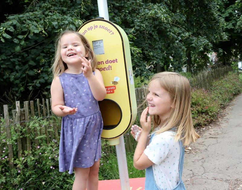 twee kinderen aan een paal met zonnecrème