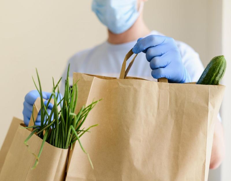 iemand met mondmasker levert boodschappen
