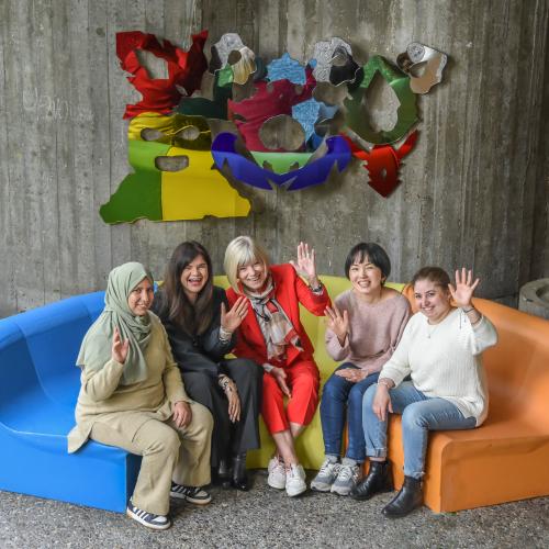 vijf enthousiaste dames op een kleurrijke bank